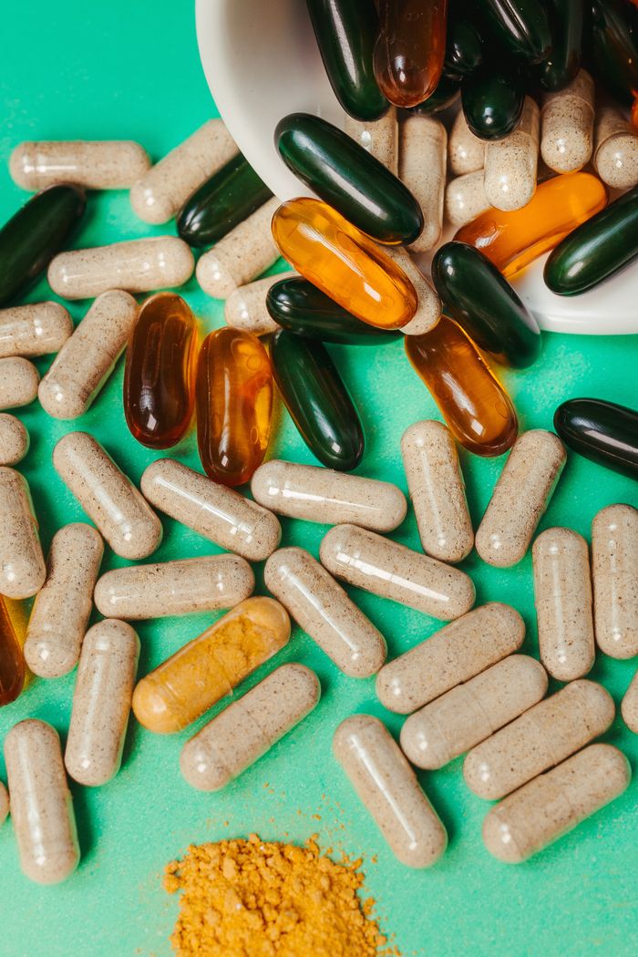 About Close-up of various vitamins and supplements scattered on vibrant green surface.